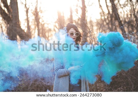 Photo of a young girl holding smoke coloured bomb in the nature