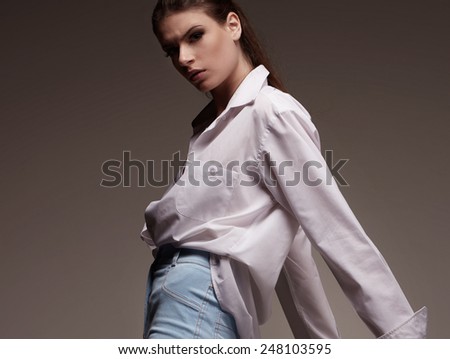 Portrait of Female fashion model with serious face in white man shirt