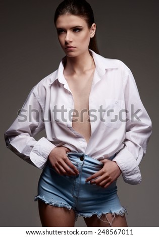 Female sexy fashion model with serious face in white man shirt on brown background