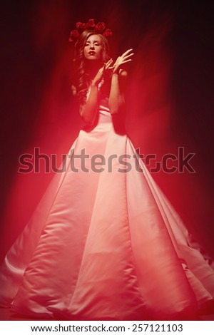 fashion model bride in a hoop from roses and in a gentle red flames flame