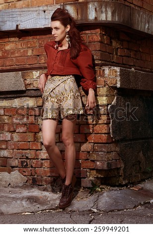 fashion vogue style woman model with make-up poising outdoor on a brick wall background