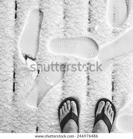 Closeup of the bare feet of an old man in slippers on new front porch winter snow