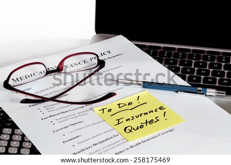 Sample Insurance Policy business document with laptop computer and calculator and reading glasses with white background and TO DO reminder note
