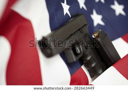 Armed United States of America gun and USA flag selective focus closeup