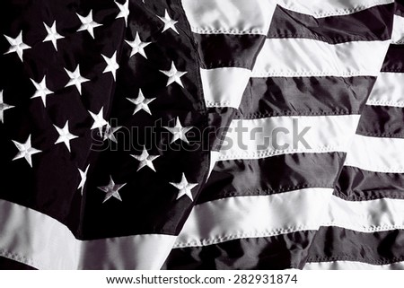 United States of America flag in black and white waving in the wind and sunlight and wind closeup