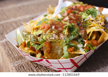 A plate of nachos with ground meat and salsa topped with cheese