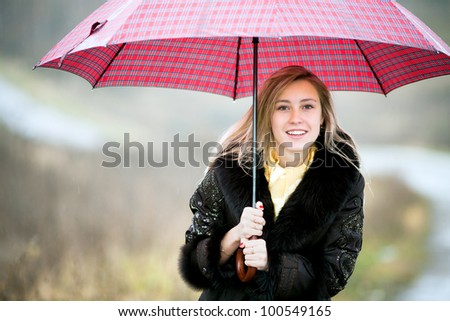 Beautiful young lady with red umbrella in rainy day isolated on autumn background