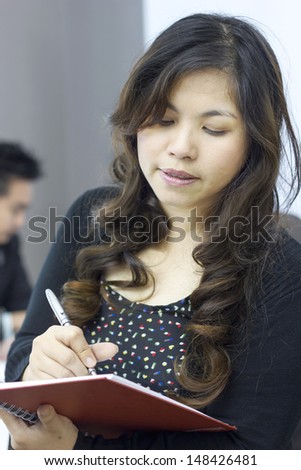Attractive woman taking notes in order not to forget something, secretary