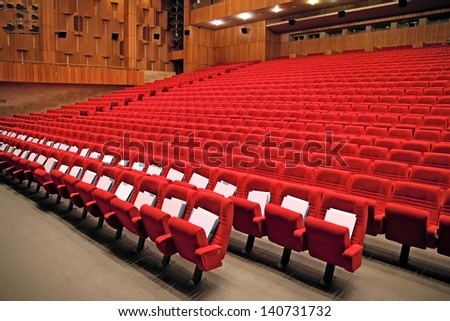 Interior of empty auditorium with red arm-chairs