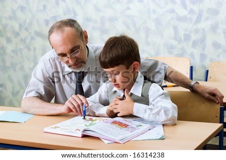Teacher and schoolboy read alphabet. Primary school.