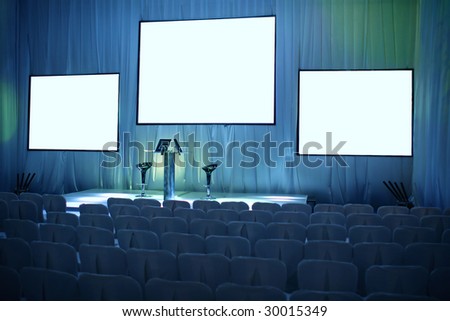 Empty big conference hall with podium and three screens