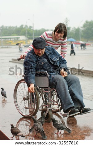 Man on a wheelchair feeding birds.