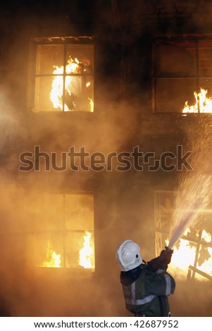 Fireman fighting a fire. The burning man jumps from a window of the second floor.