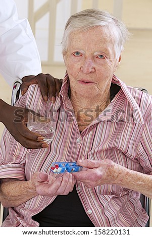 nurse assisting disabled elderly woman to take medicine