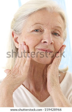 Senior woman applying anti-aged cream