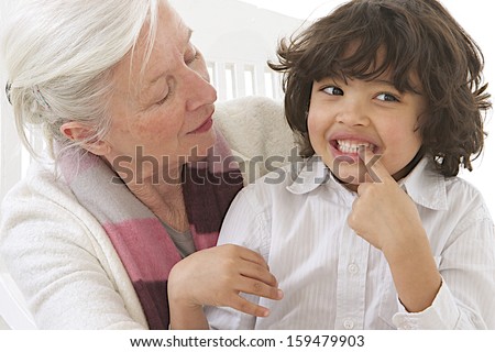 Lost milk tooth, cute boy with long hair showing his missing teeth to his grandmother