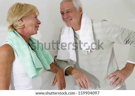 Happy senior couple exercising in fitness center  towel on the shoulder - with a look of complicity