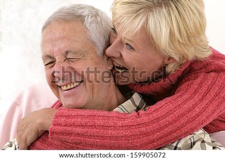 Senior life style -couple of happy elderly senior  - she is biting the ear of her husband with tenderness-Isolated over white background.