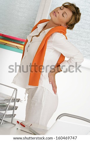 Nice Business woman with back pain after long work on chair.