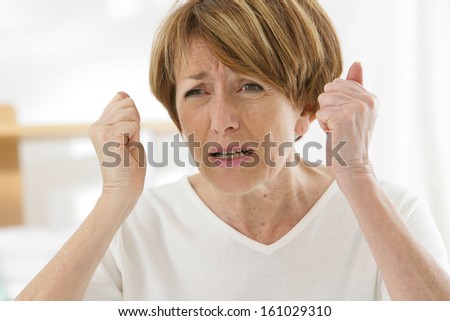 A strong image of a very stress and angry senior woman screaming and clenching her fists..