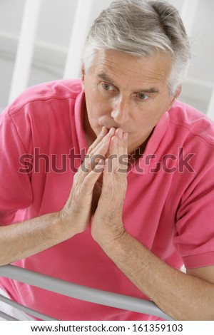 Elderly man with hands near his face looking down thinking- anxious face