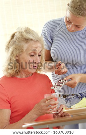 Home care nurse helping elderly lady to take her daily medicine.