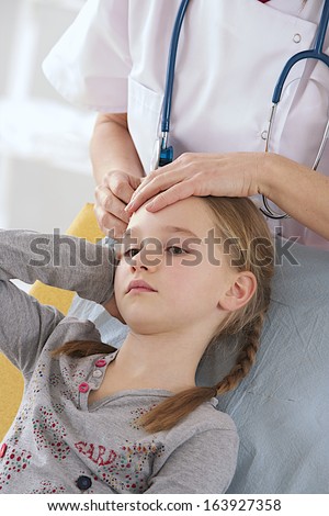 Sick little girl having medical check up while having hear-ache