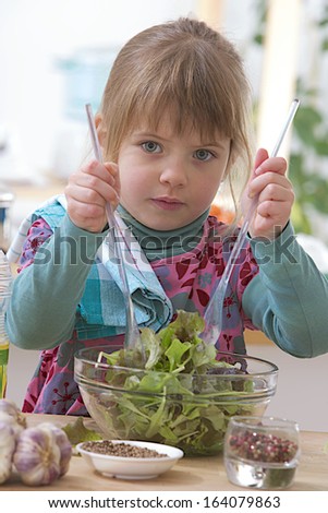 little cook with fresh green salad - she is mixing the salad