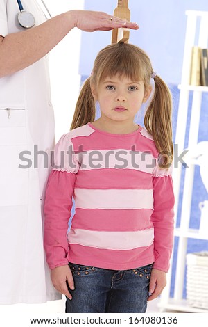 Pediatrician measure height of little girl at medical office