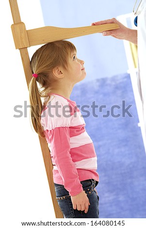 Pediatrician measure height of little girl at medical office - profile view