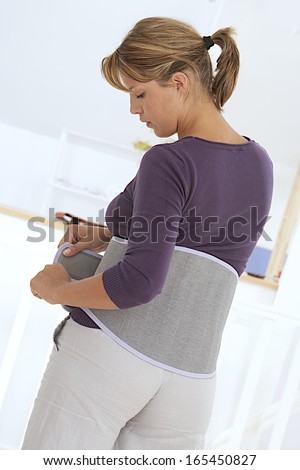 young woman wearing a back support belt  -  back view