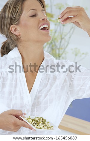 portrait of attractive caucasian smiling woman  eating bean sprouts