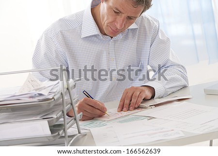 middle aged  and handsome businessman in his office working and looking at finance