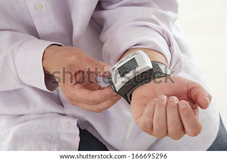 mature man using a home blood pressure machine to check his vital statistics.
