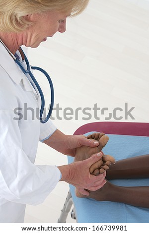 Caucasian doctor checking  African American female patient\'s flat foot