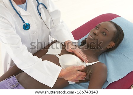 Caucasian doctor examining African-American woman breast - Cancer prevention