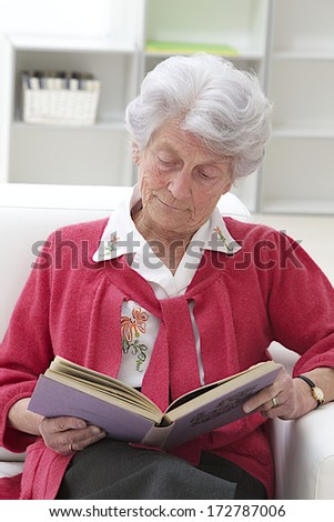 Smiling Grey haired senior woman relaxing at home reading a book