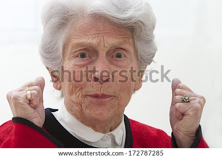 Closeup portrait of angry, furious elderly woman raising clenched hand