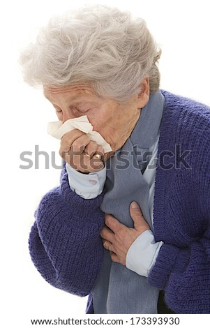 Elderly woman having a cold, blowing nose