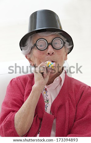 happy mature woman with funny big eye-glasses , party hat and noise maker