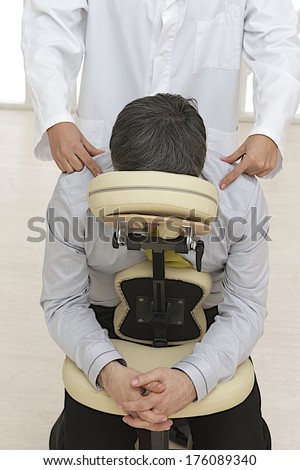 Businesswoman sitting on massage chair, enjoying shoulder and back massage