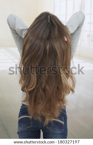 Brunette lady holding long hairs, view from back side isolated on white