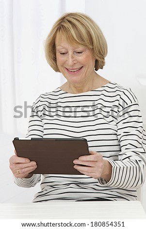 Smiling senior woman at home connected on internet