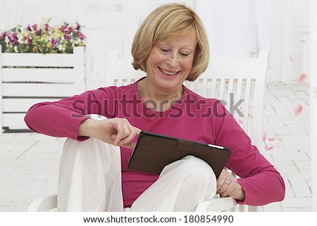 Smiling senior woman at home connected on internet  on her terrace