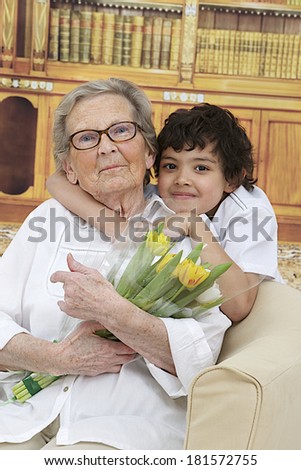Little boy giving flowers to his grand mother  grandmother\'s day  in the library at home