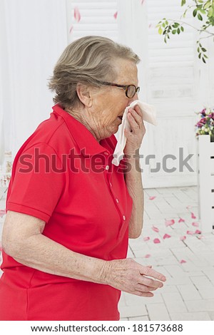 Senior woman sneezing into a tissue