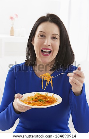 business woman wearing blue dress enjoying a healthy salad at work
