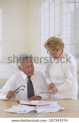 comfortable senior couple at home organizing  bills and administrative paper