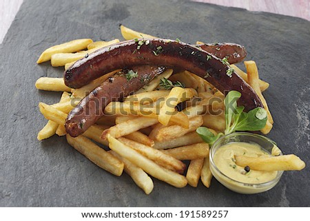grilled sausage and french fries with mustard on slate plate