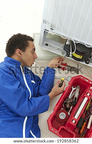 Repairman makes refrigerator appliance troubleshooting and maintenance works